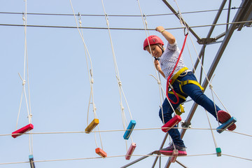 Little girl climbing on an outdoor ropes course.