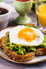 Avocado egg sandwich with whole grain bread on wooden background. Copy space