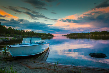 Boat on the shore. Dawn. Reflection of the sunrise in the water. Karelia. Russia. Ladoga lake.