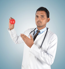 Young male doctor holding a red apple , health care idea