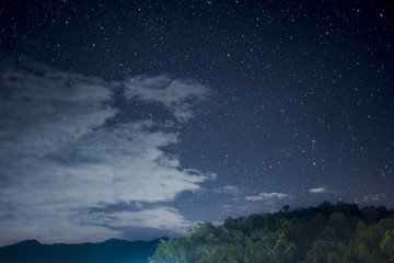 Beautiful night scape with dark blue sky with a lot of star white cloud and the green mountain. View from the village in the forest at the north part of Thailand.