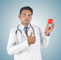 Young male doctor holding a red apple and thumb up , health care idea