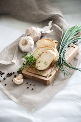 Three pieces of freshly baked baguette on a wooden board and fresh herbs..