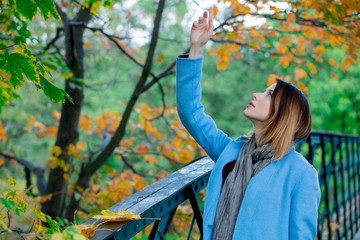 Young redhead woman in blue coat resting in autum park