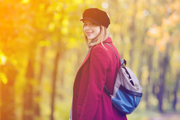 woman in red coat and backpack have a rest in autum park