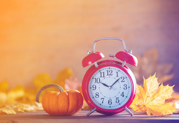 Vintage alarm clock and maple tree leaves with pumpkins