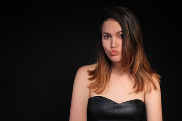 Fototapeta premium Girl in a black dress blowing a kiss
