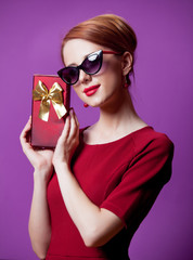 Portrait of young redhead woman in sunglasses with gift box