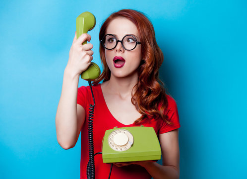 Portrait of young redhead woman with handset