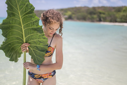Woman holding a big leaf on the beach