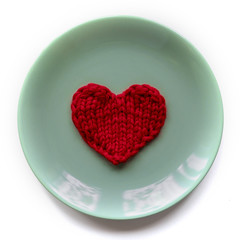 red knitted heart lies on a blue plate