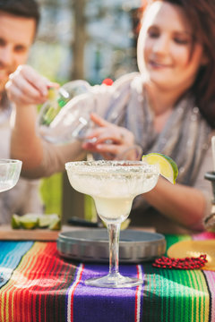 Cinco: One Margarita Sits On Table While Woman Makes Another