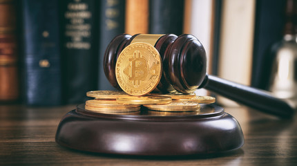 Judge or auction gavel and bitcoins on a wooden desk
