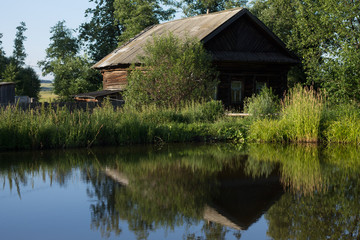 Fototapeta na wymiar house in the village near the pond in the summer heat