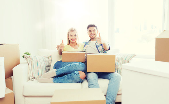 happy couple with boxes showing thumbs up at home