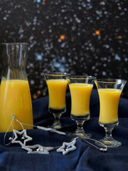 Homemade eggnog in bottle and three glasses with Christmas decoration on dark background.