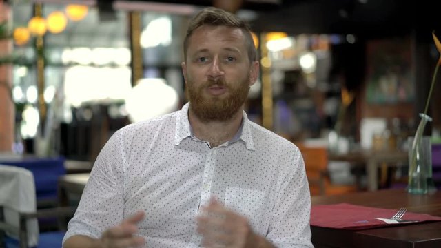 Handsome man looks unhappy while having an argument with someone, steadycam shot
