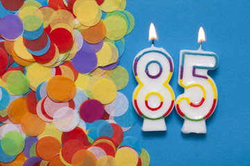 Number 85 celebration candle with party confetti