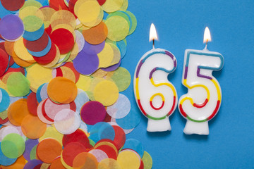 Number 65 celebration candle with party confetti