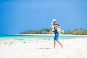 Father and little girls have a lot of fun on white sandy beach