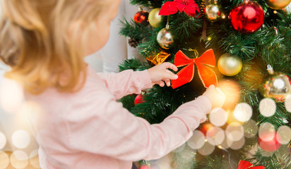 close up of little girl decorating christmas tree