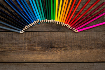 Colored pencils in gradient order located folded on wooden table. School concept. Copy space