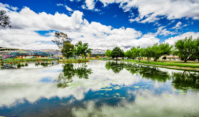 Fototapeta premium Beautiful day of an artificial lake located in the midle of a park, with the reflection in the water, in the city of Cayambe, Ecuador