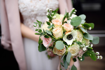 Bride holding stylish wedding flowers bouquet