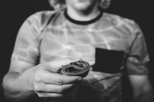 Black and white photo of someone showing a roll of bills