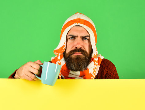 Hipster with serious face holds warm tea or coffee cup