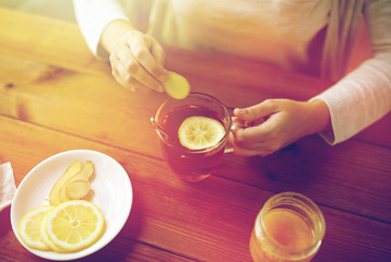 close up of woman adding ginger to tea with lemon