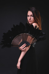 Young woman with a black feather fan and hat