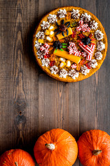 Homemade pie for halloween decorated gummy spiders among pumpkins on wooden background top view copyspace