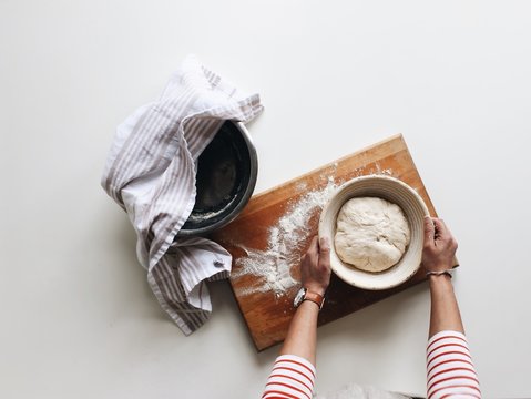 Overhead image of someone holding dough in a proofing basket