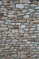 Stone wall background of colorful stones with matt film effect. Vertical photo