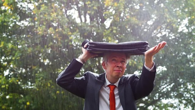 Businessman sheltering underneath his bag in the rain