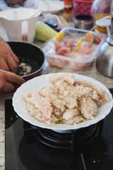 Person  breading with breadcrumbs and corn, the steaks of chicken to fry.
