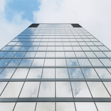 Exterior of modern office building, sky reflecting in windows, low angle view