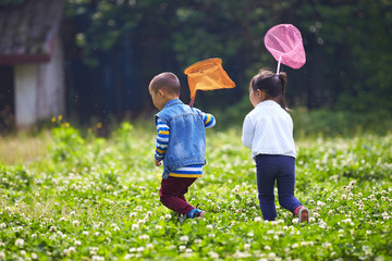 two kids catching the butterfly outdoor in the park