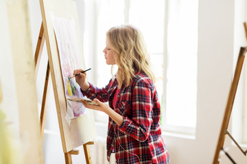 student girl with easel painting at art school