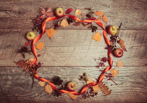 Autumn arrangement of leaves, apples and berries on a wooden background with free space for text. Top view, season concept, toned retro effect