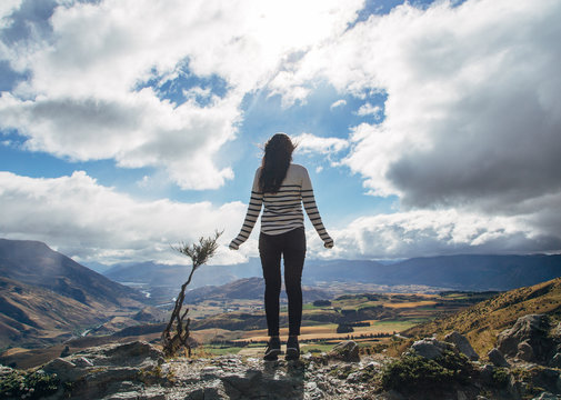 Young woman standing alone above a mountain range