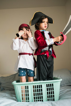 two young pirate boys in their laundry basket boat at sea on a bed