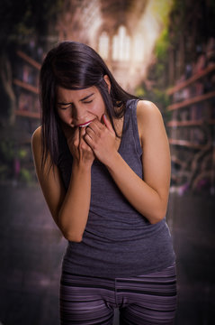 Beautiful and lonely girl suffering of anorexy, putting his fingers in her mouth to induce to vomit, in a blurred background