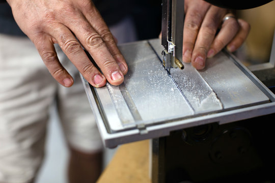 Man cutting a piece of plastic with a band saw