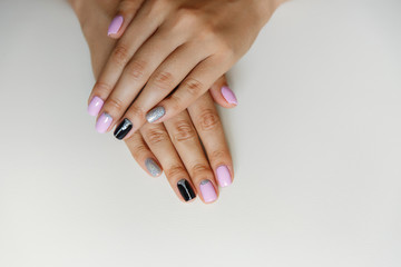 Natural nails with colorful manicure, pink, black and silver polish on women nails. Nails of woman...