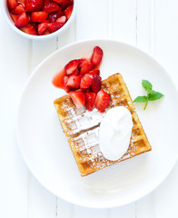 Pets (Belgian) waffles with strawberries and whipped cream.