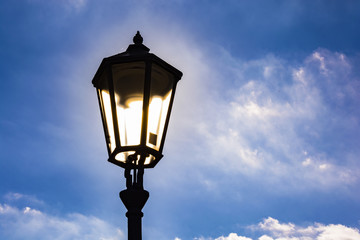 Fototapeta na wymiar Lighting street lamp under blue sky with fairy tale´s clouds.
