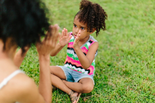 Mother and daughter playing patty cake in the park
