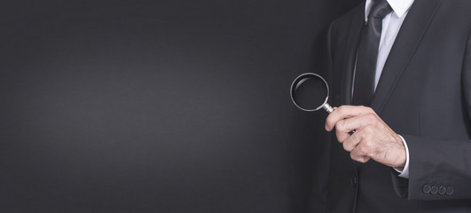 suit businessman holding a magnifying glass